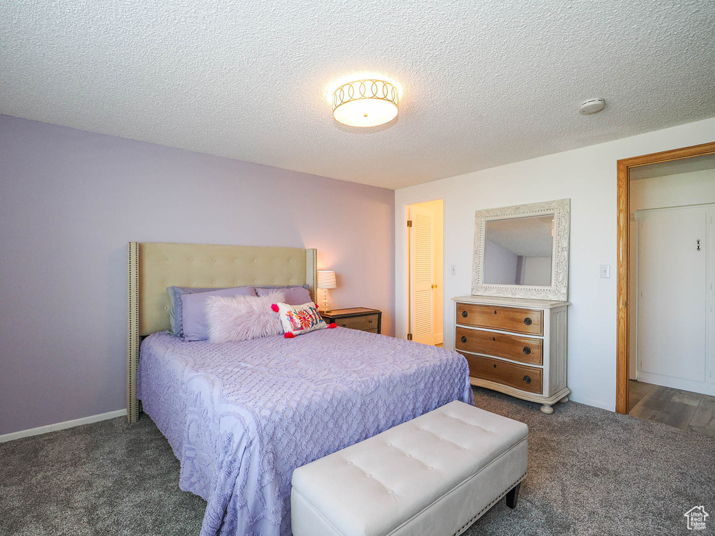 Bedroom with dark colored carpet and a textured ceiling