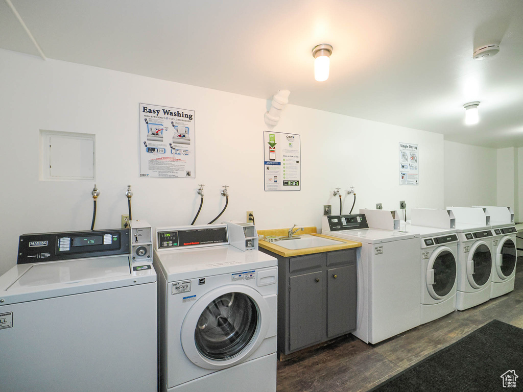 Laundry room featuring dark hardwood / wood-style floors, sink, separate washer and dryer, and cabinets