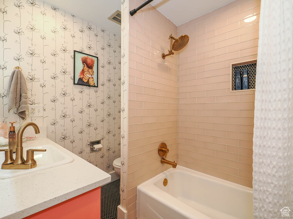 Full bathroom featuring vanity, tiled shower / bath, and toilet