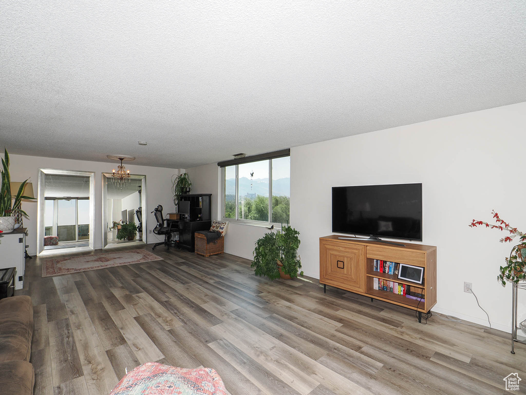 Unfurnished living room featuring an inviting chandelier, a textured ceiling, and hardwood / wood-style flooring