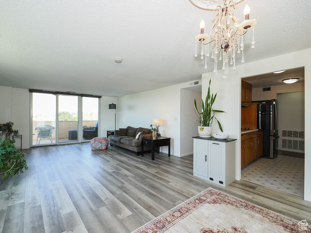 Living room featuring a textured ceiling, a notable chandelier, and light hardwood / wood-style floors