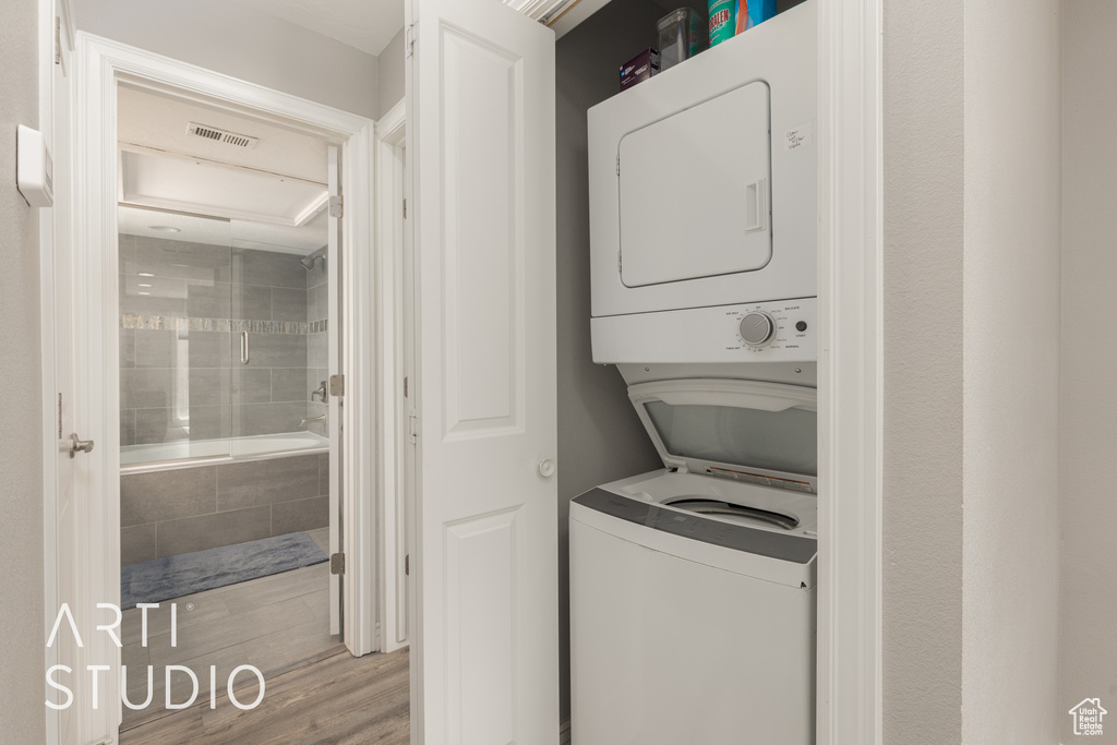 Laundry room with stacked washer and dryer and hardwood / wood-style floors