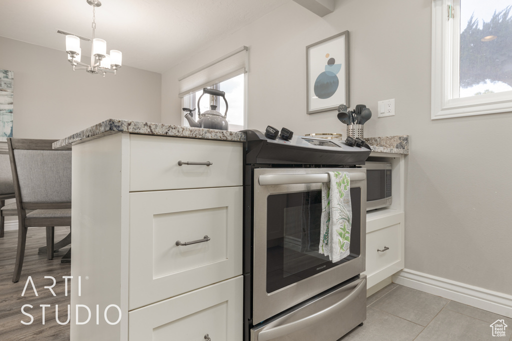 Kitchen featuring light tile patterned flooring, white cabinets, double oven range, and plenty of natural light