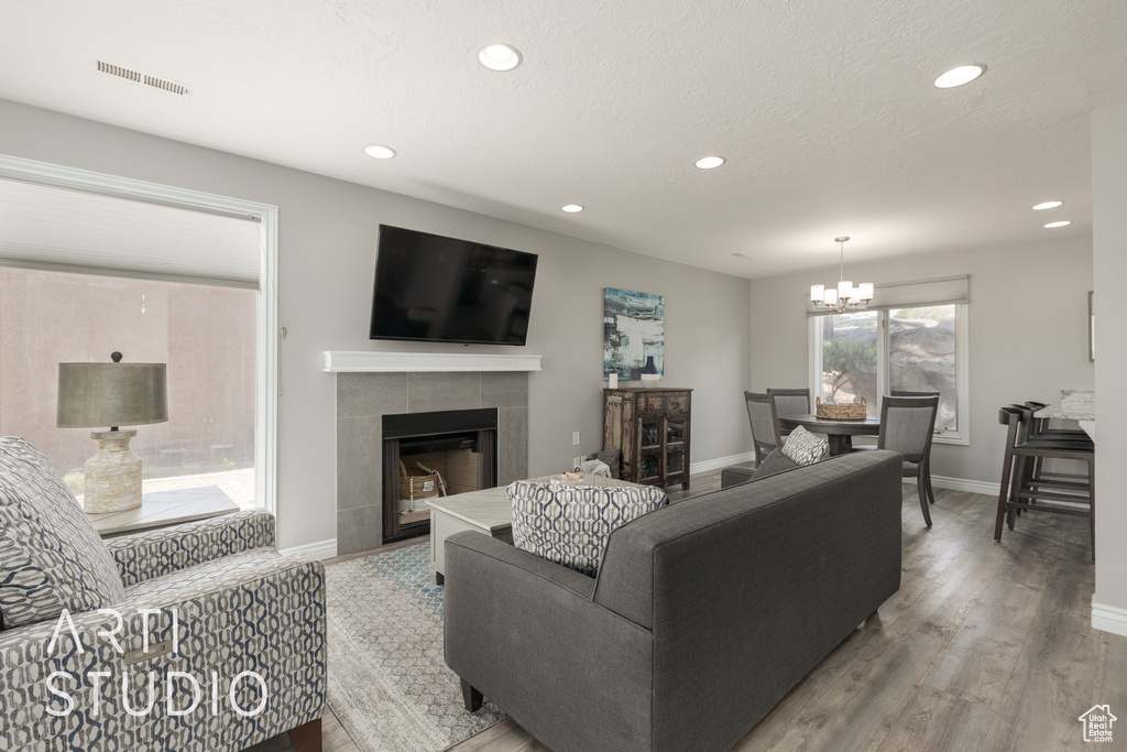 Living room featuring hardwood / wood-style flooring, a notable chandelier, and a tile fireplace