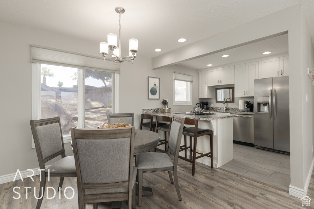 Dining space with hardwood / wood-style floors, sink, and an inviting chandelier