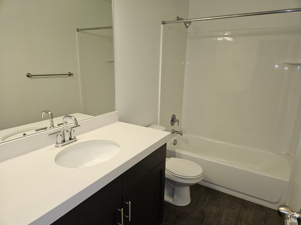 Full bathroom featuring hardwood / wood-style flooring, toilet, vanity, and tub / shower combination