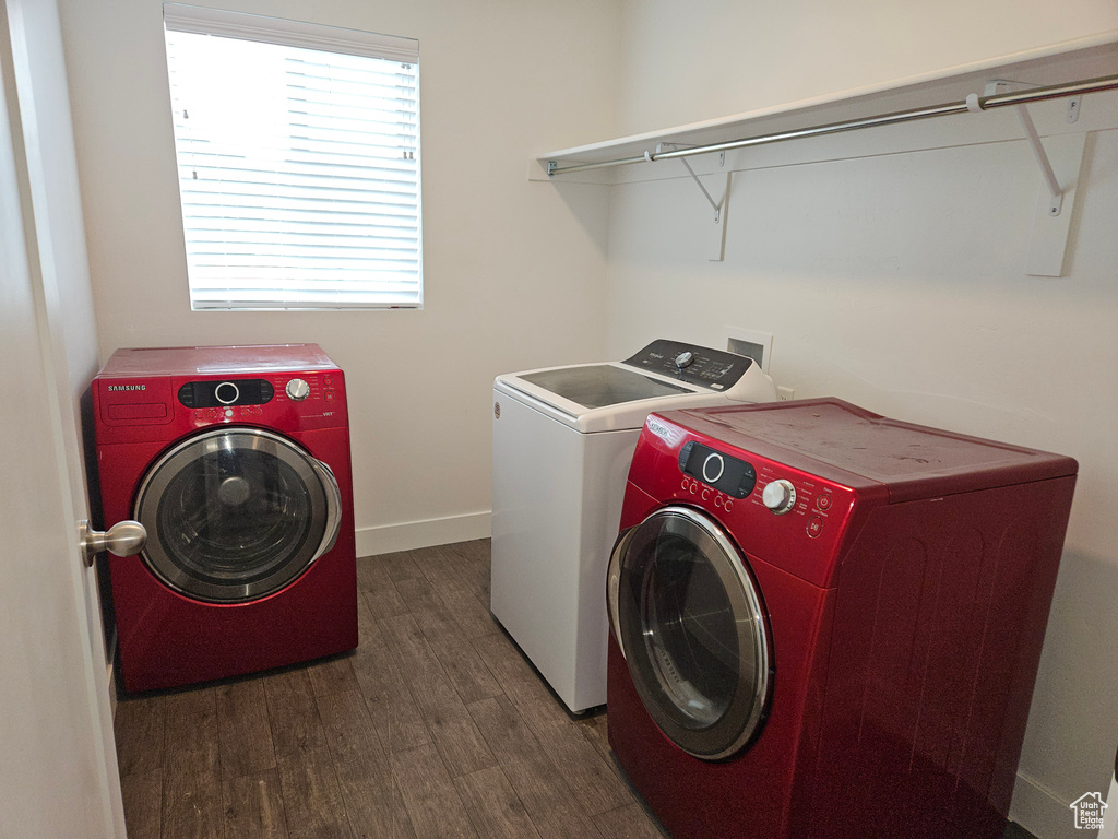 Clothes washing area with dark hardwood / wood-style floors and washing machine and clothes dryer