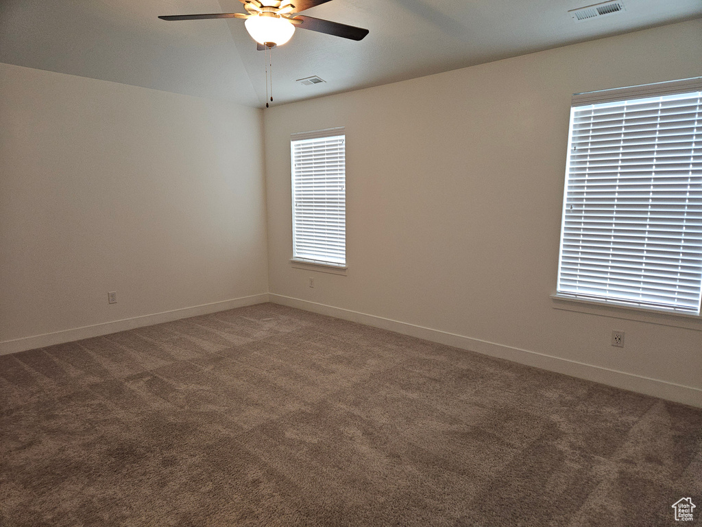 Unfurnished room with ceiling fan and dark carpet