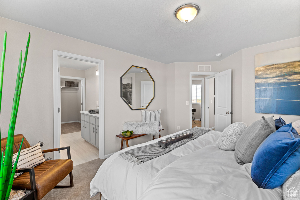 Bedroom with ensuite bathroom and light wood-type flooring