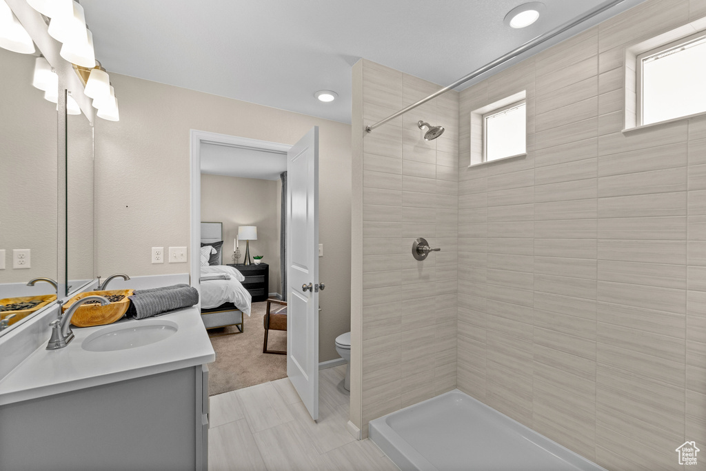 Bathroom with tile patterned floors, vanity, a tile shower, and toilet