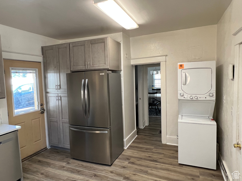 Kitchen with stacked washer and dryer, stainless steel refrigerator, and wood-type flooring