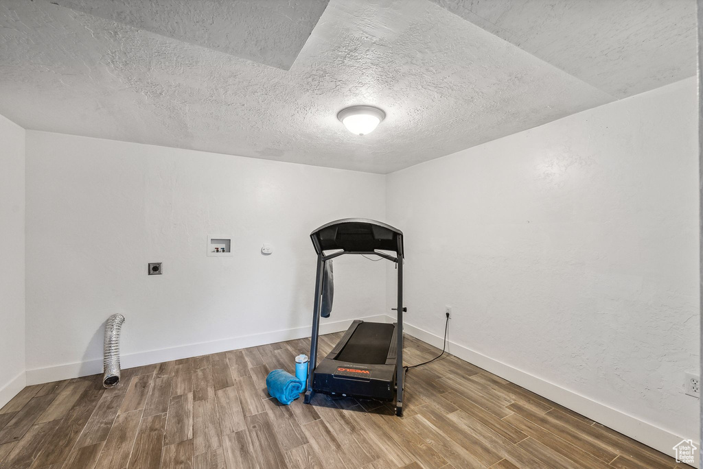 Exercise area with wood-type flooring and a textured ceiling