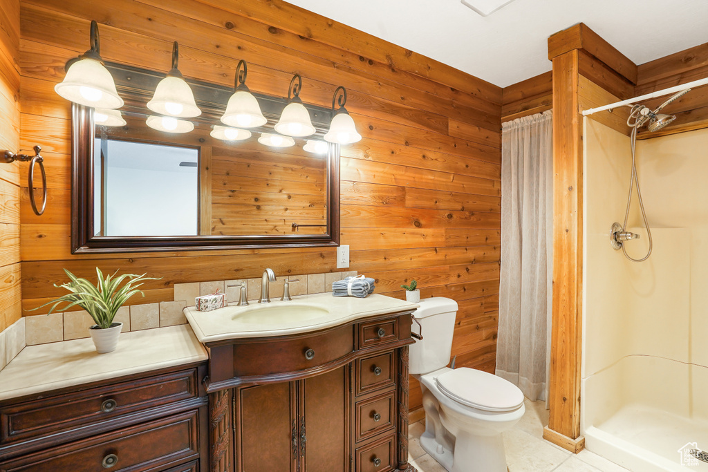 Bathroom featuring wooden walls, tile patterned floors, toilet, vanity, and curtained shower