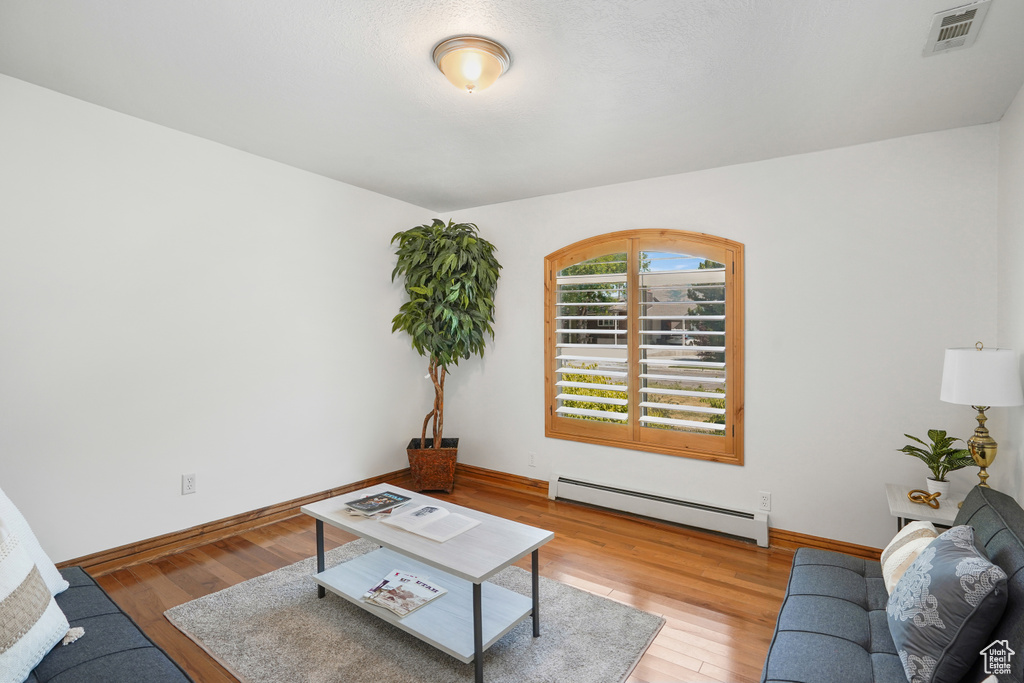 Living room with a baseboard radiator and light hardwood / wood-style flooring