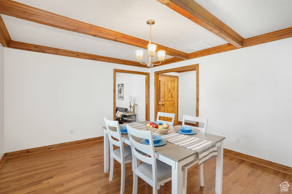 Dining space featuring beam ceiling, a notable chandelier, and light hardwood / wood-style flooring