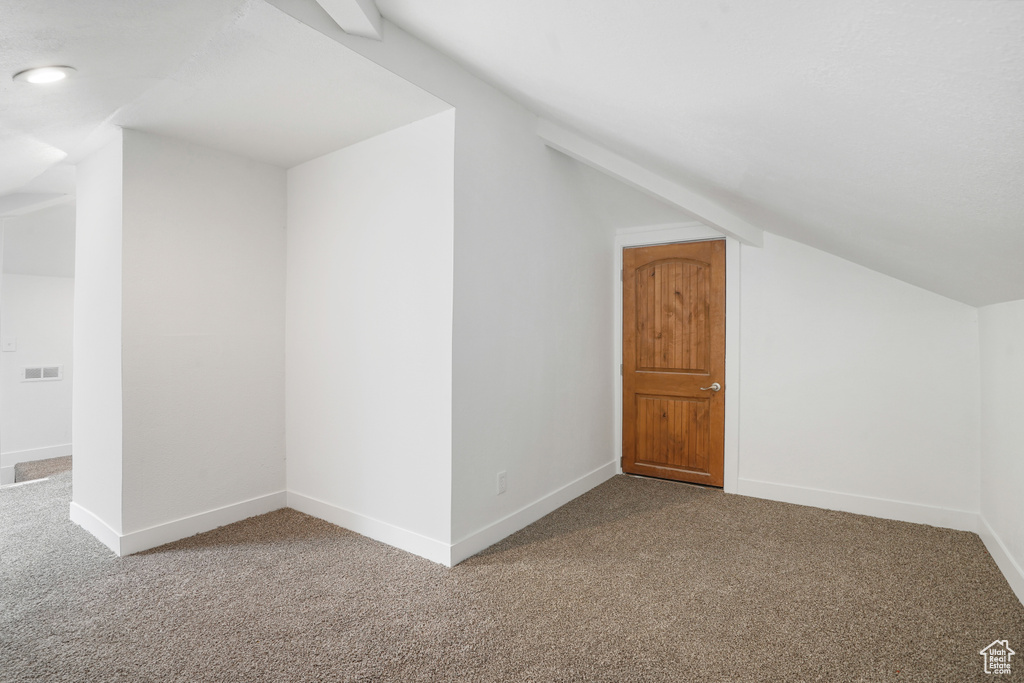 Additional living space with vaulted ceiling and carpet