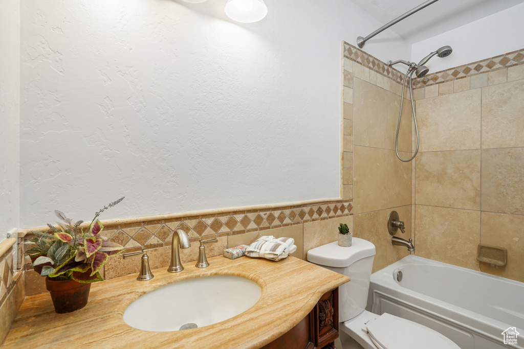 Full bathroom featuring vanity, tiled shower / bath combo, toilet, and tasteful backsplash