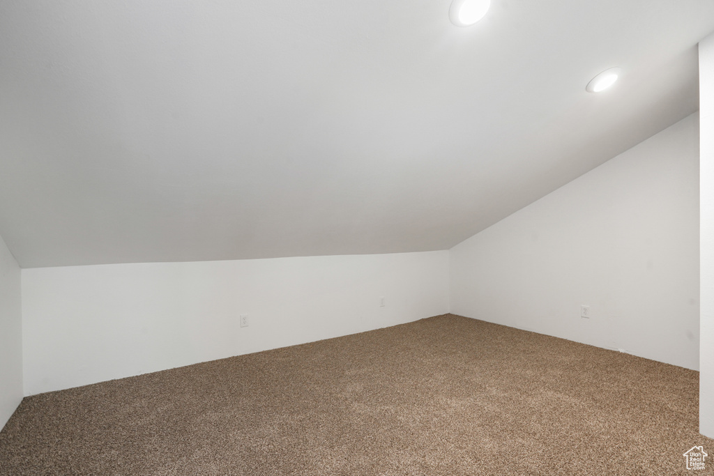 Bonus room with carpet flooring and vaulted ceiling