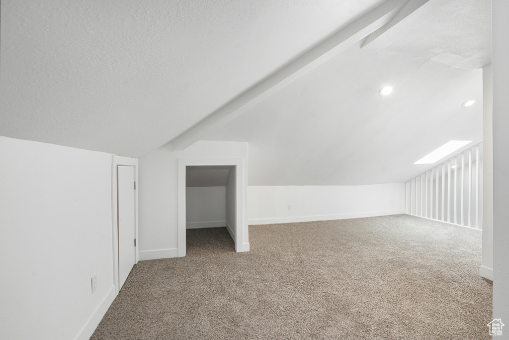 Additional living space with carpet floors, a textured ceiling, and lofted ceiling