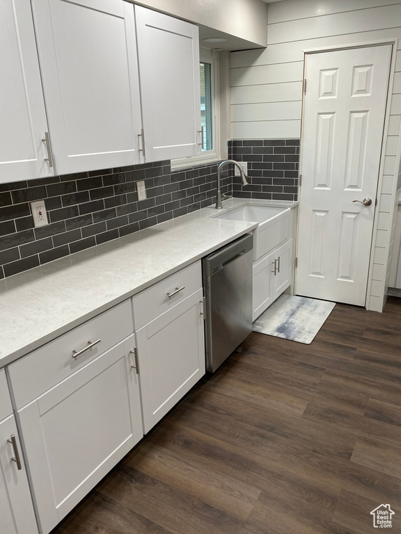 Kitchen featuring decorative backsplash, stainless steel dishwasher, dark wood-type flooring, and white cabinets