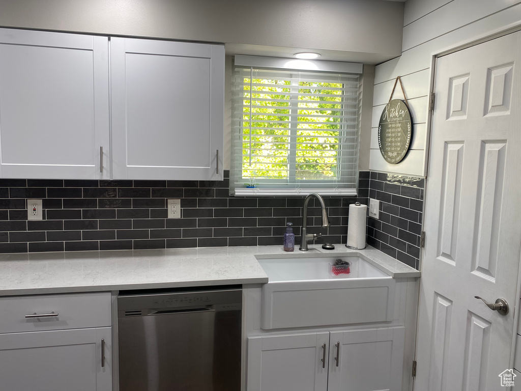 Kitchen with sink, stainless steel dishwasher, tasteful backsplash, and white cabinets