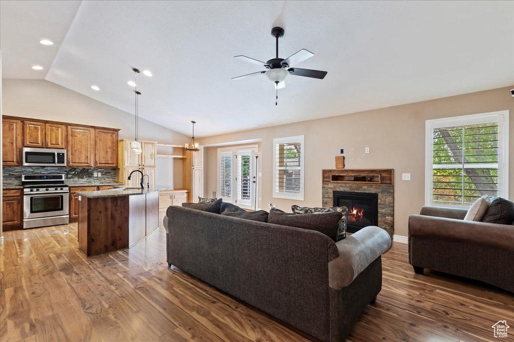 Living room with lofted ceiling, a fireplace, wood-type flooring, and a wealth of natural light