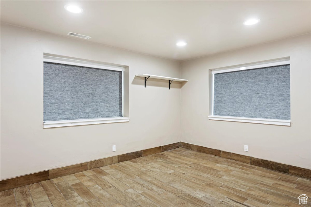 Empty room with light hardwood / wood-style floors and a wealth of natural light