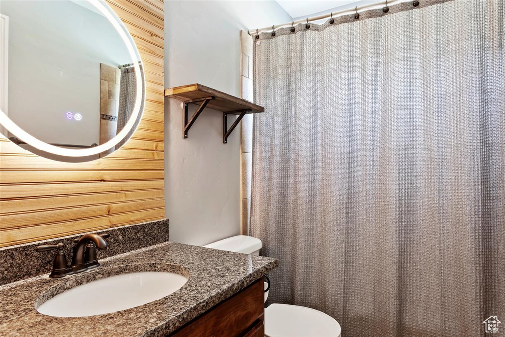 Bathroom with wood walls, toilet, and vanity