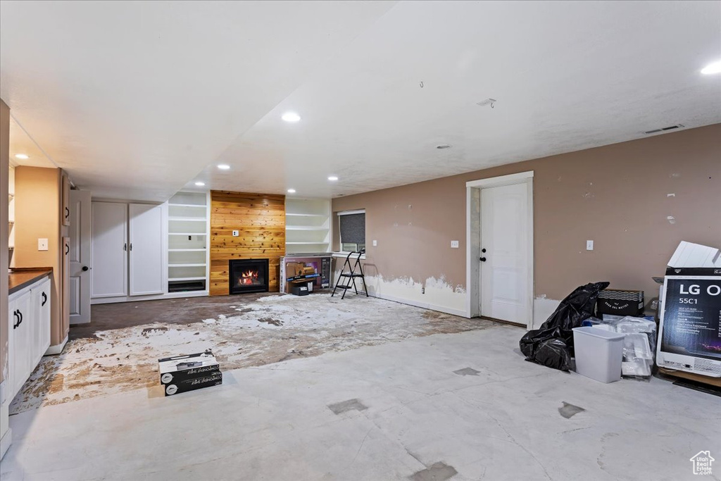 Unfurnished living room featuring wooden walls and a large fireplace