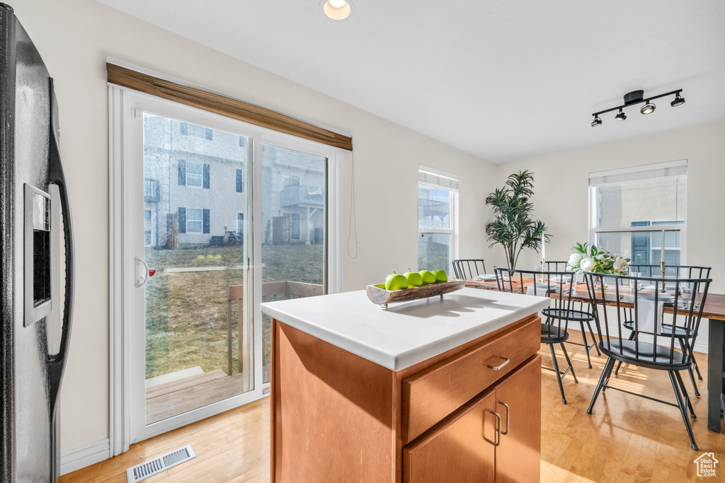 Kitchen with light wood-type flooring, a kitchen island, track lighting, and a wealth of natural light