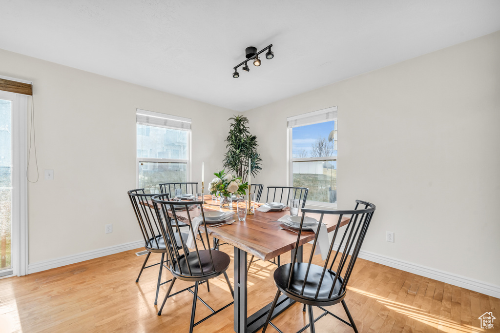 Dining room with light hardwood / wood-style flooring and rail lighting