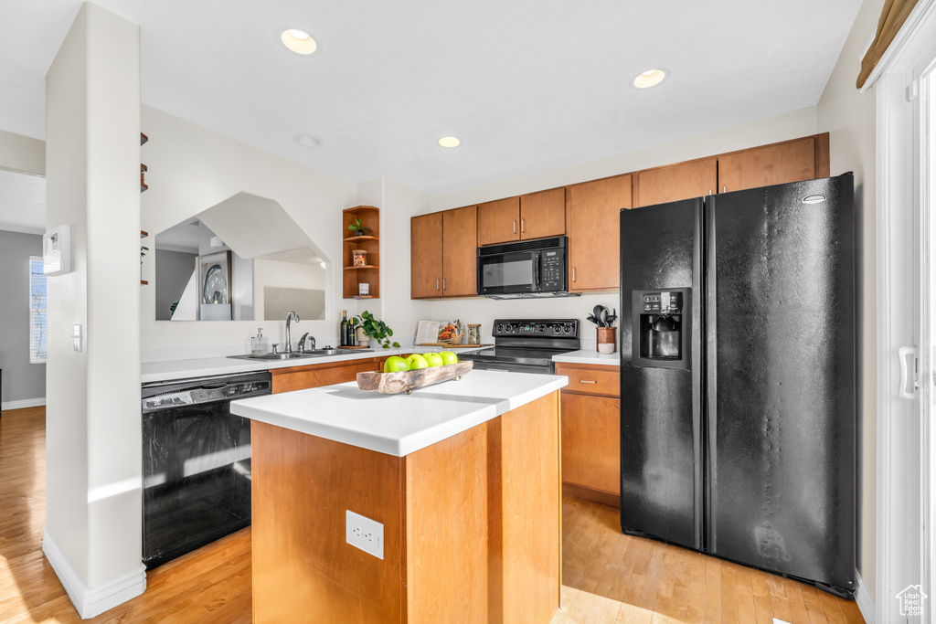 Kitchen with a kitchen island, sink, black appliances, and light hardwood / wood-style floors