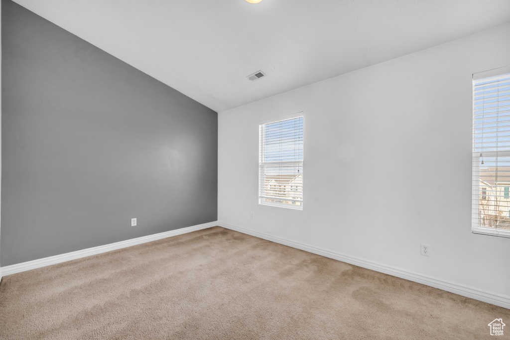 Spare room featuring lofted ceiling and light colored carpet