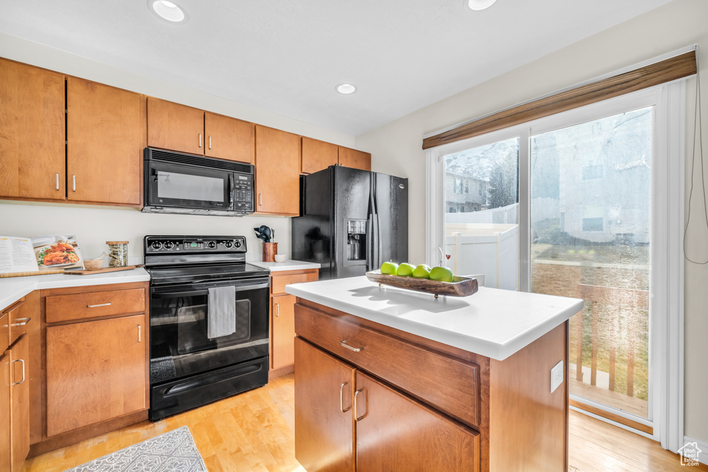 Kitchen with a center island, black appliances, a wealth of natural light, and light wood-type flooring