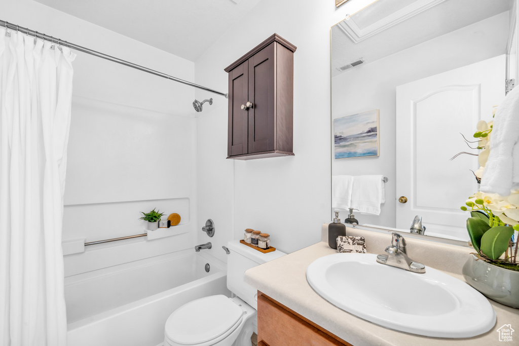 Full bathroom with vanity, shower / tub combo with curtain, and toilet