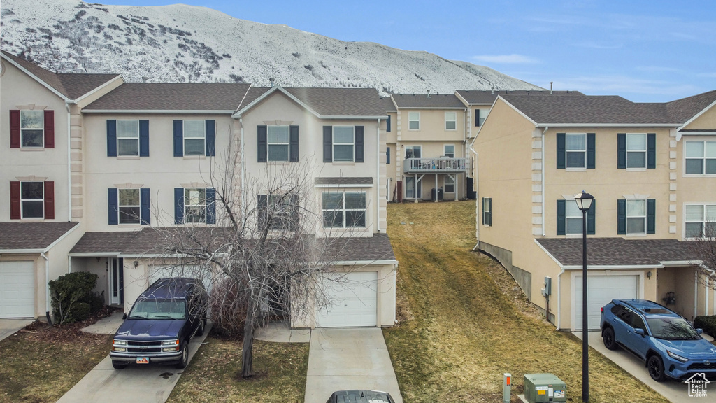 Townhome / multi-family property with a garage, a front lawn, and a mountain view