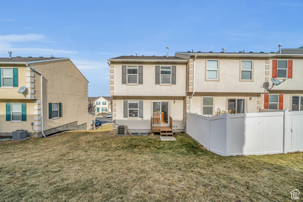 Back of property with a yard and central AC