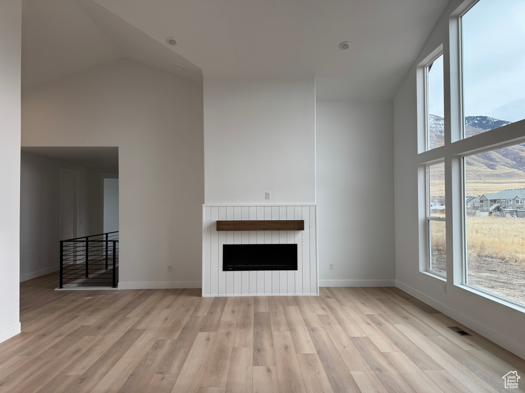 Unfurnished living room featuring a mountain view, light hardwood / wood-style flooring, and vaulted ceiling