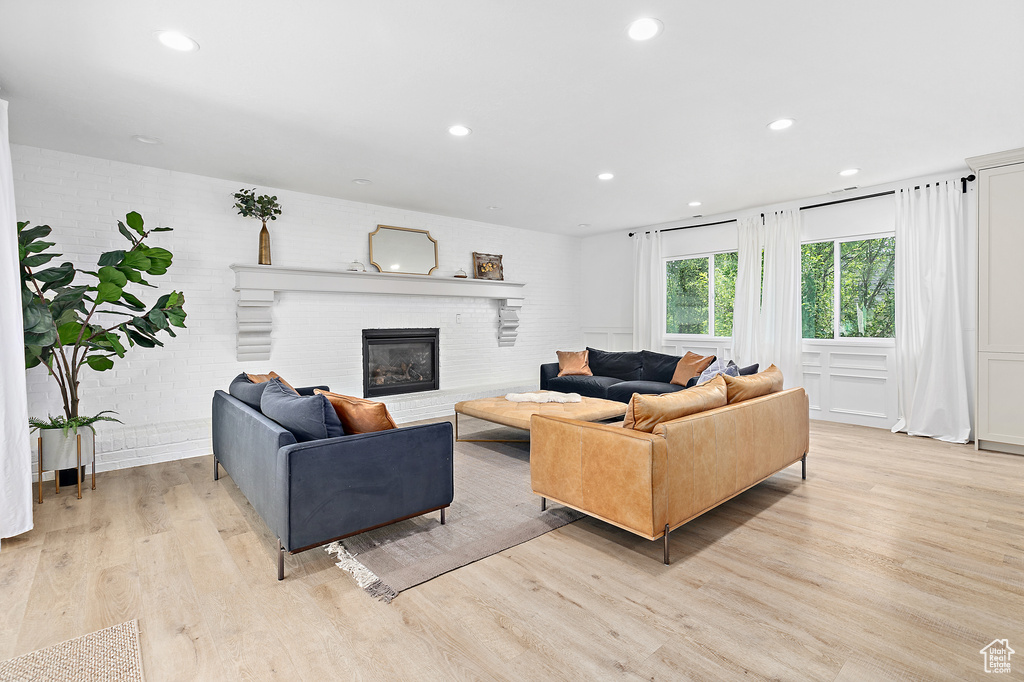 Living room with brick wall, light wood-type flooring, and a brick fireplace