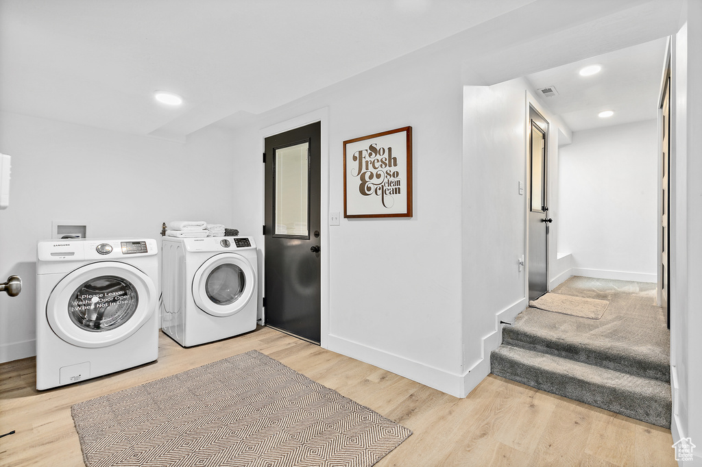 Laundry room with light hardwood / wood-style flooring and washing machine and dryer