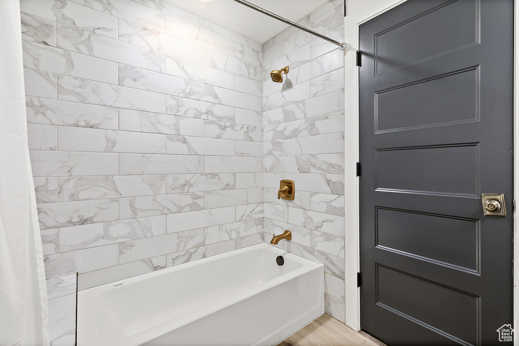 Bathroom with hardwood / wood-style flooring and shower / tub combo with curtain