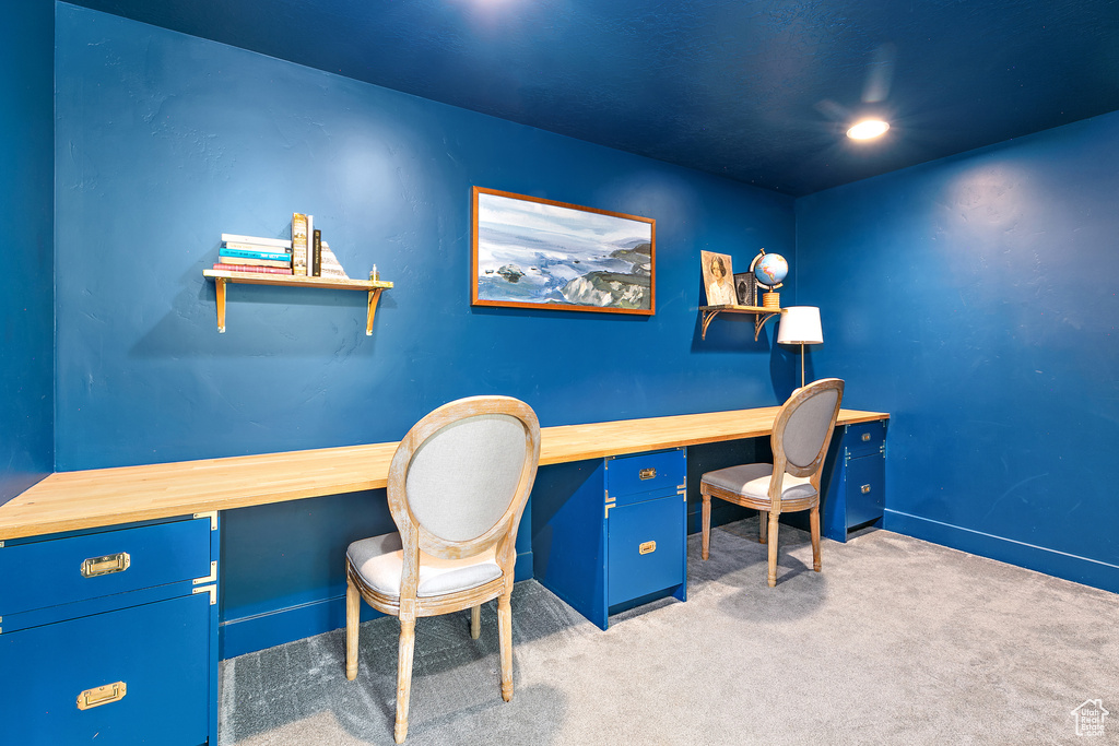 Office space featuring built in desk and light colored carpet