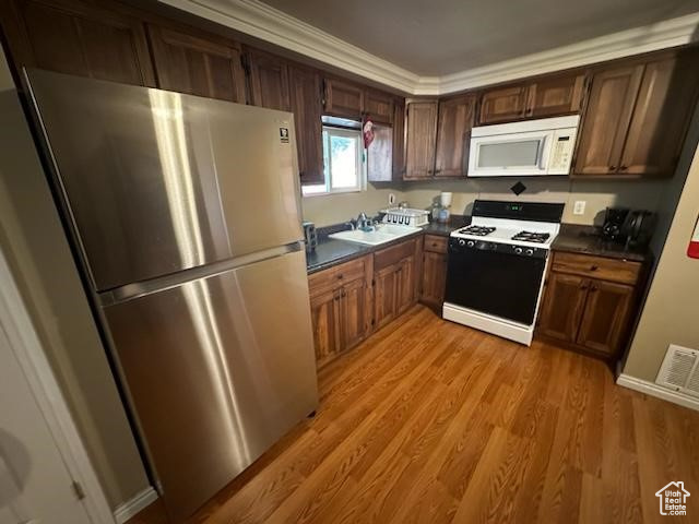 Kitchen with ornamental molding, sink, light hardwood / wood-style flooring, and white appliances