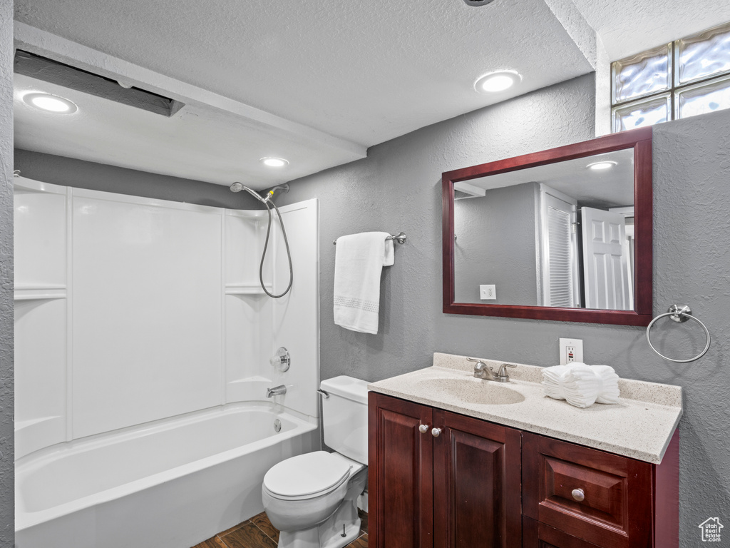 Full bathroom with a textured ceiling, tub / shower combination, toilet, vanity, and hardwood / wood-style flooring