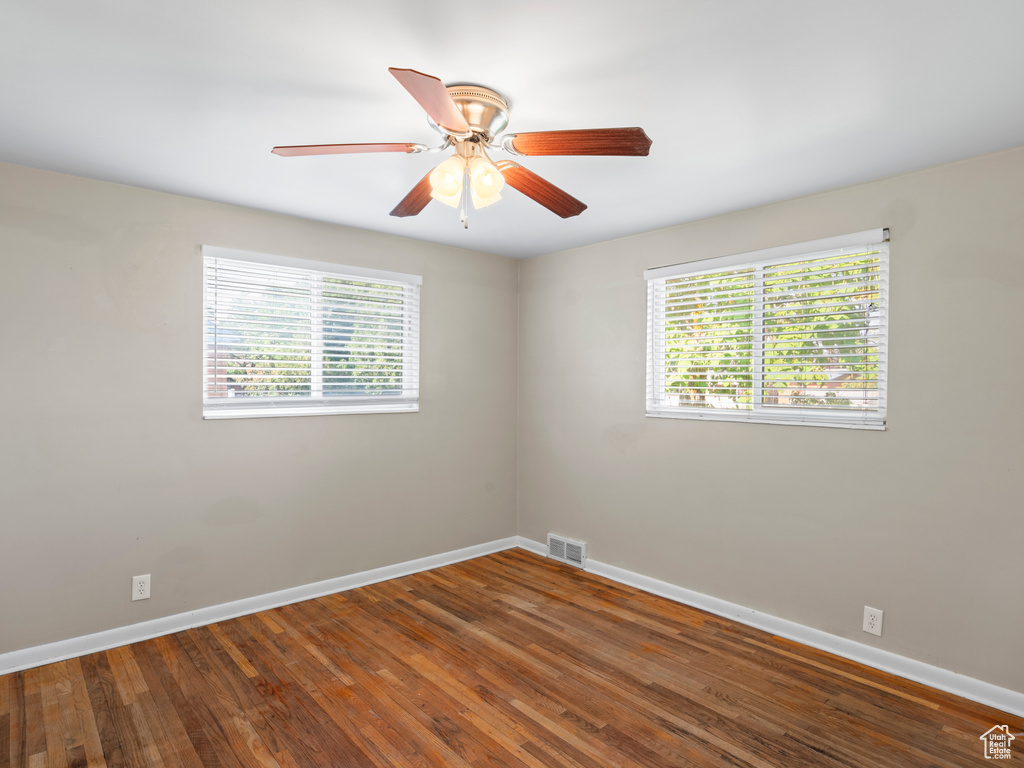 Spare room with ceiling fan, wood-type flooring, and plenty of natural light