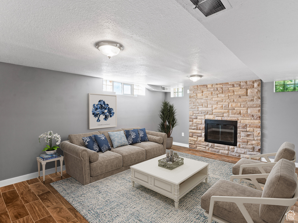 Living room with a fireplace, a textured ceiling, hardwood / wood-style floors, and plenty of natural light