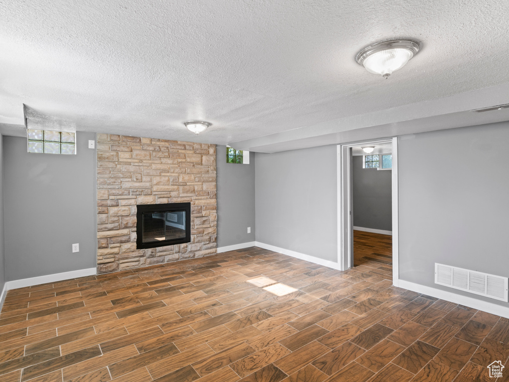 Unfurnished living room with a fireplace, a healthy amount of sunlight, dark wood-type flooring, and a textured ceiling