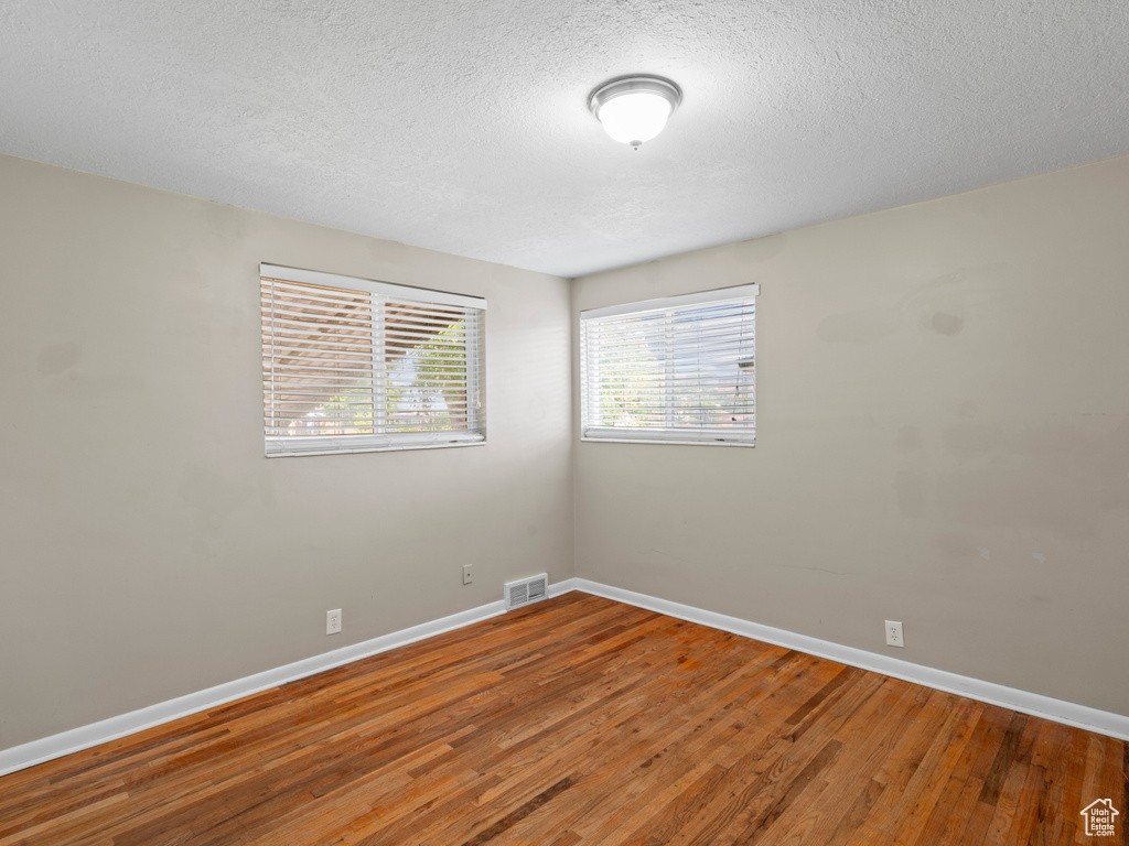 Unfurnished room with a textured ceiling and hardwood / wood-style floors