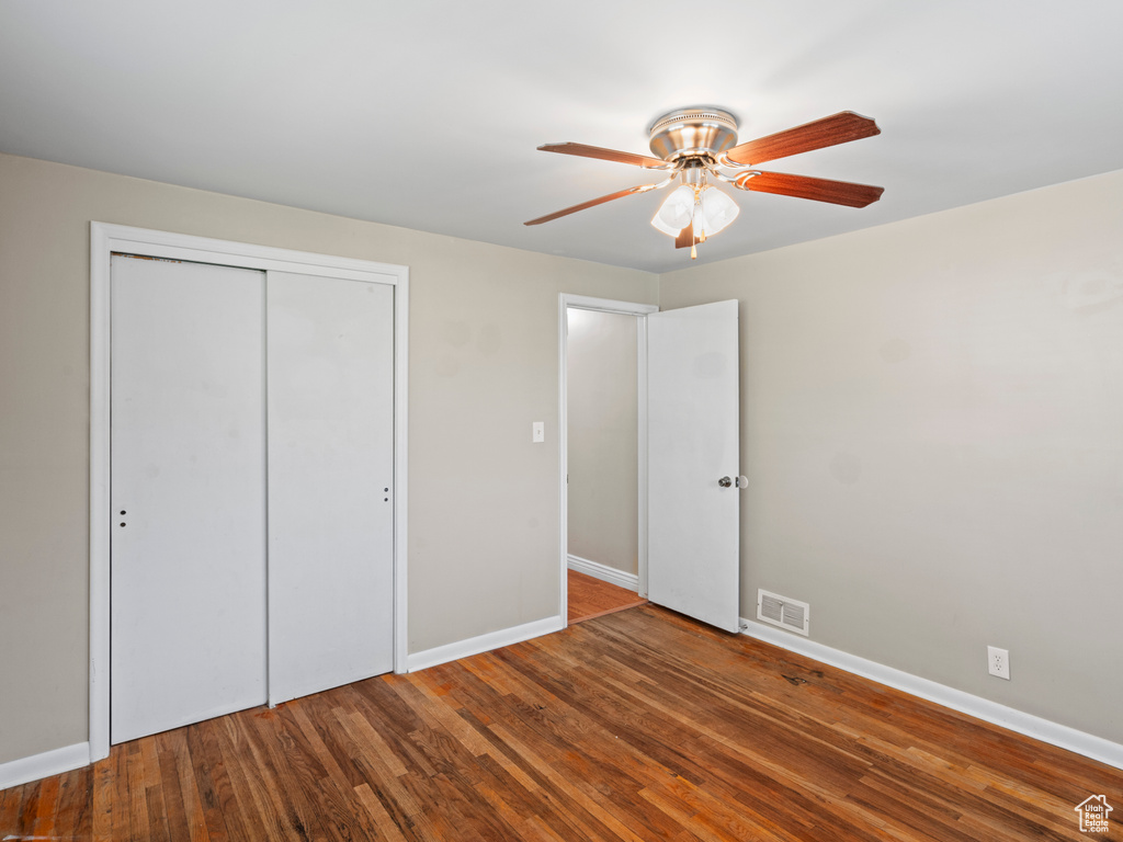 Unfurnished bedroom with ceiling fan, hardwood / wood-style flooring, and a closet