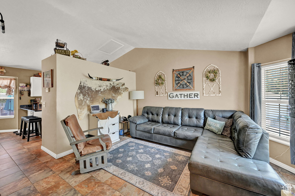 Tiled living room featuring a healthy amount of sunlight and vaulted ceiling